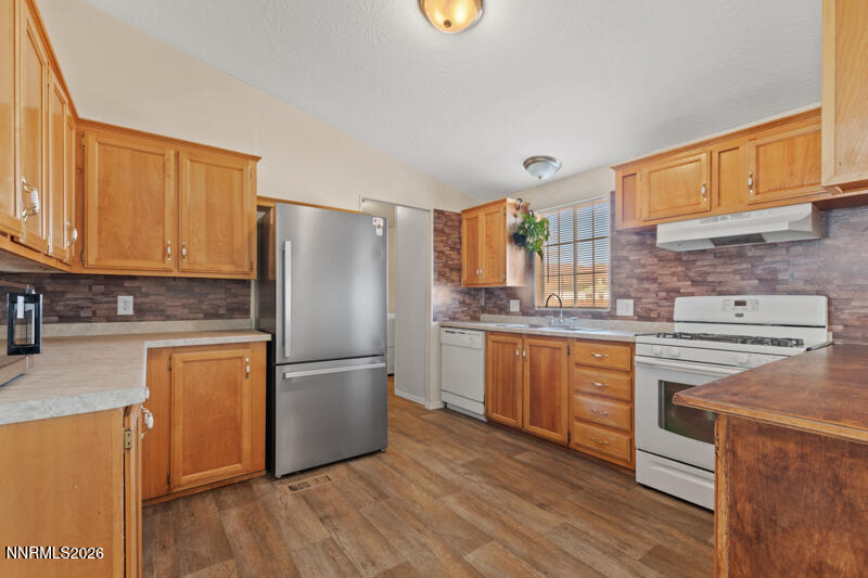 2575 Tonopah Street Silver Springs, NV 89429 - Photo 9 of 22 a kitchen with stainless steel appliances granite countertop a refrigerator a stove top oven and sink with wooden floors