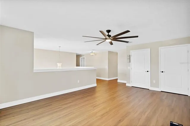 an empty room with wooden floor fan and windows