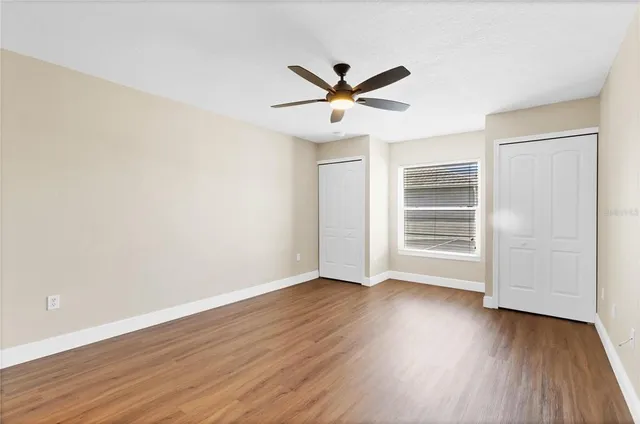 a view of empty room with wooden floor and ceiling fan
