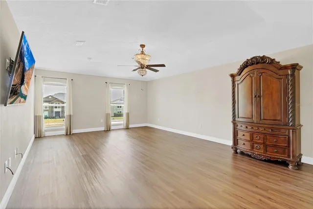 an empty room with wooden floor and ceiling fan