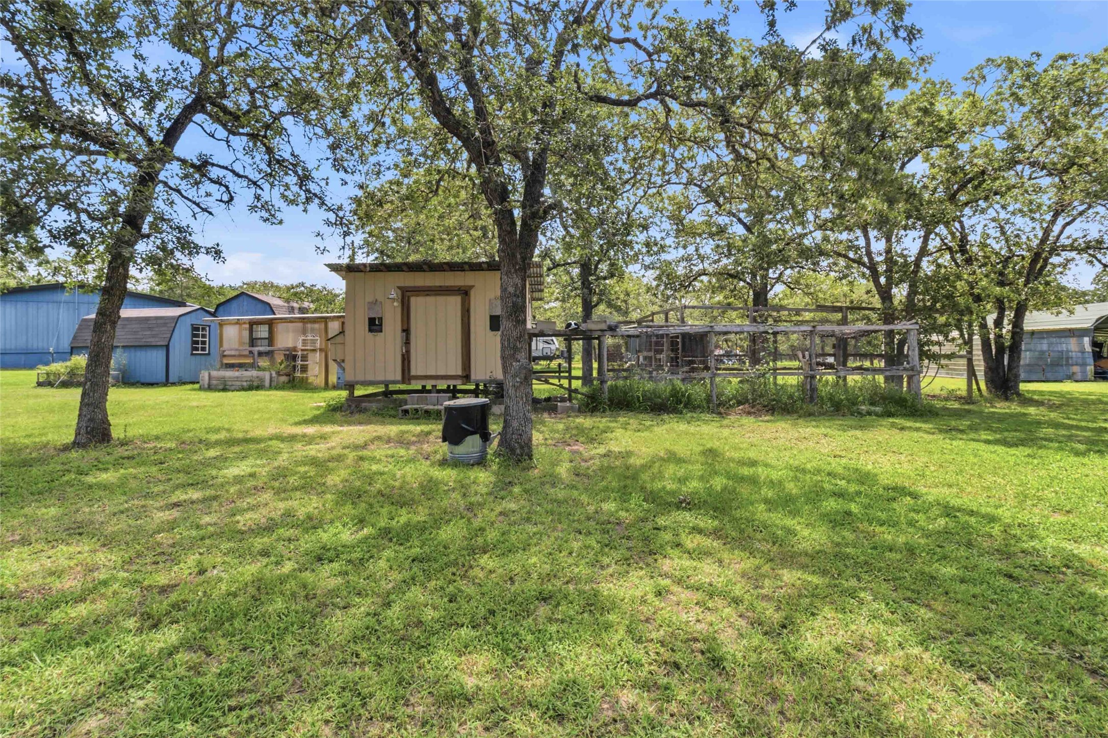 7921 Vista Ranch Road Smithville, TX 78957 - Photo 28 of 39 A verdant backyard offers ample space with various outbuildings nestled under mature trees.