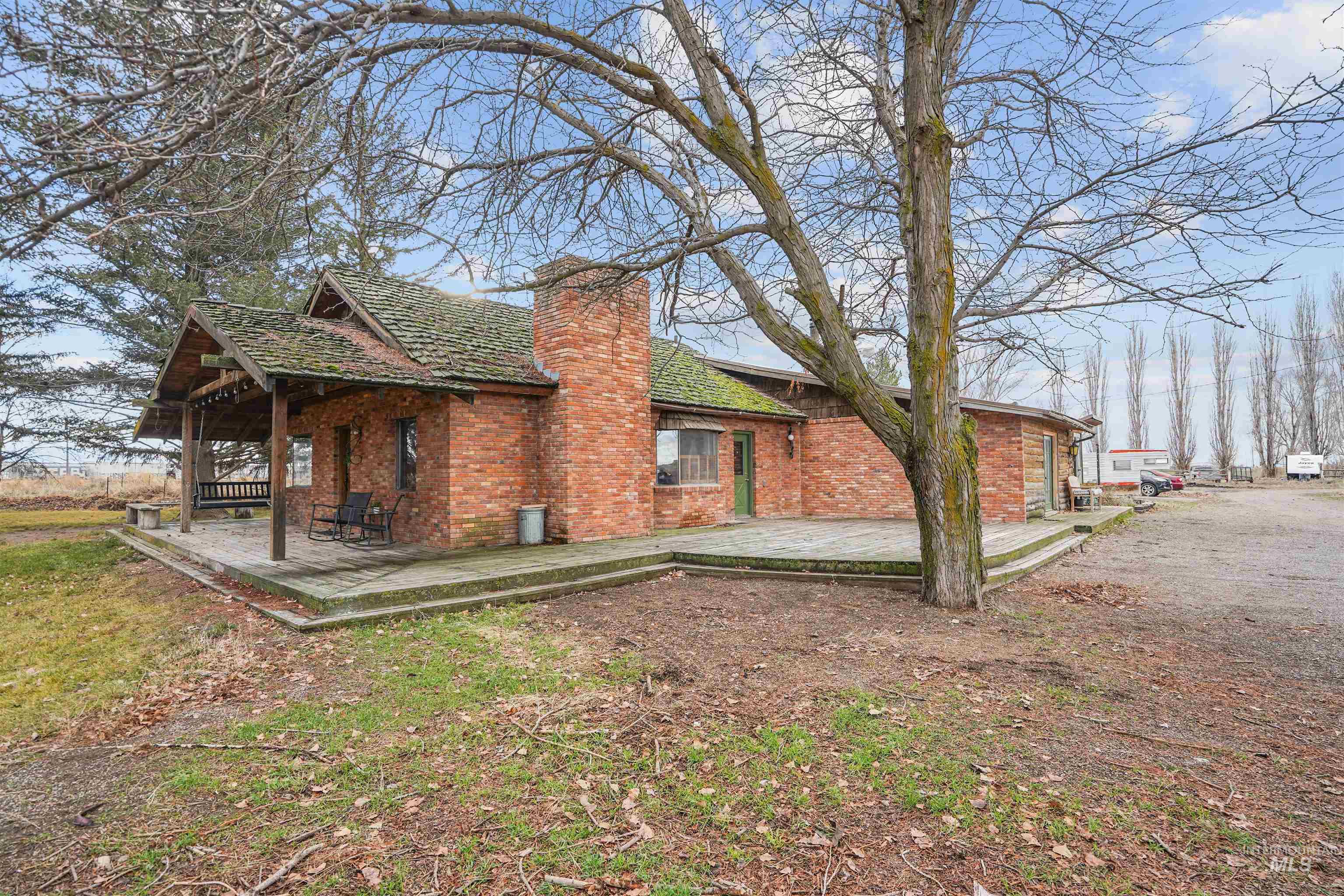 View of side of property with a wooden deck, brick siding, and a chimney
