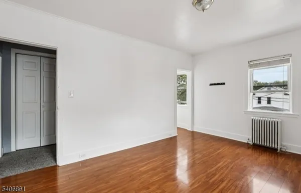 an empty room with wooden floor cabinet and windows
