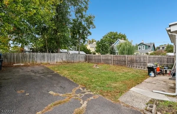 a view of a backyard with large trees and wooden fence
