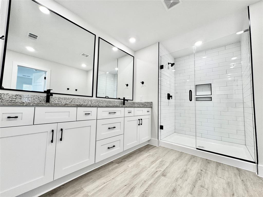 8749 Scotty's Lk Lane The Colony, TX 75056 - Photo 20 of 33 Bathroom with wood finished floors, a shower stall, double vanity, and recessed lighting