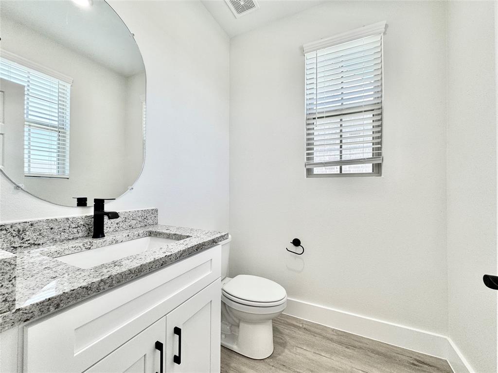 8749 Scotty's Lk Lane The Colony, TX 75056 - Photo 7 of 33 Half bathroom with wood finished floors, baseboards, toilet, vanity, and plenty of natural light