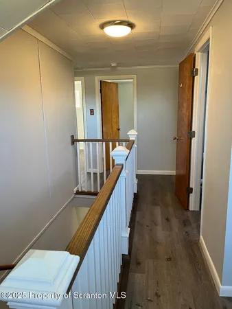 a view of a hallway with wooden floor and stairs