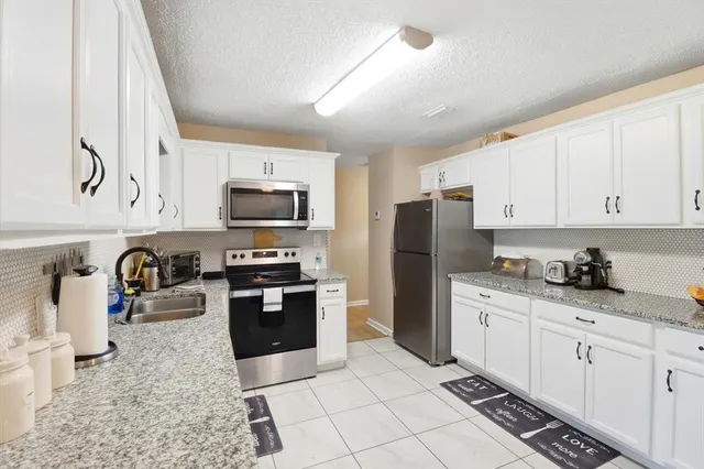 a kitchen with stainless steel appliances granite countertop a refrigerator stove top oven and sink