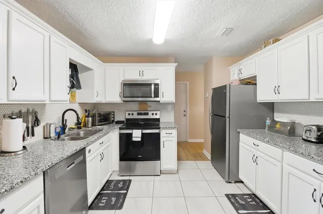 a kitchen with granite countertop a refrigerator stove and sink