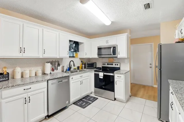 a kitchen with stainless steel appliances granite countertop a refrigerator and a stove top oven