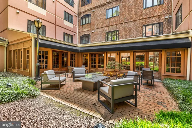 a flower garden with potted plants and big trees