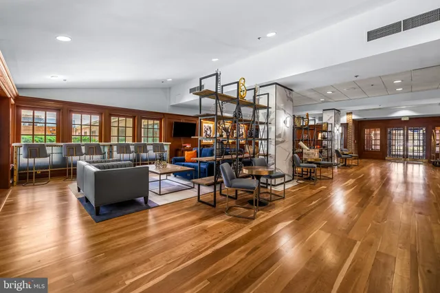 a living room with couches and kitchen view with wooden floor