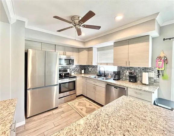a kitchen with stainless steel appliances kitchen island granite countertop a refrigerator a sink dishwasher a stove and white cabinets with wooden floor