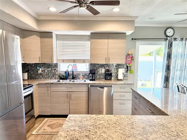 a kitchen with stainless steel appliances granite countertop a refrigerator a sink a stove and white cabinets