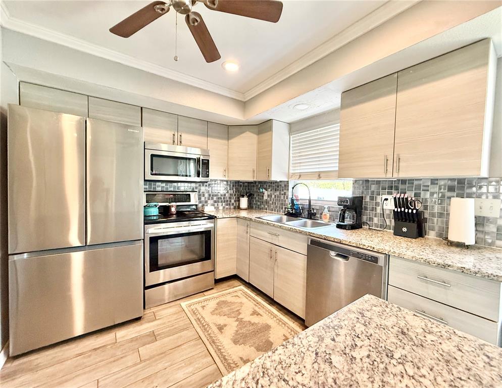 1784 Taylor Lake Place Largo, FL 33778 - Photo 9 of 24 a kitchen with stainless steel appliances granite countertop a refrigerator a stove a sink and a microwave