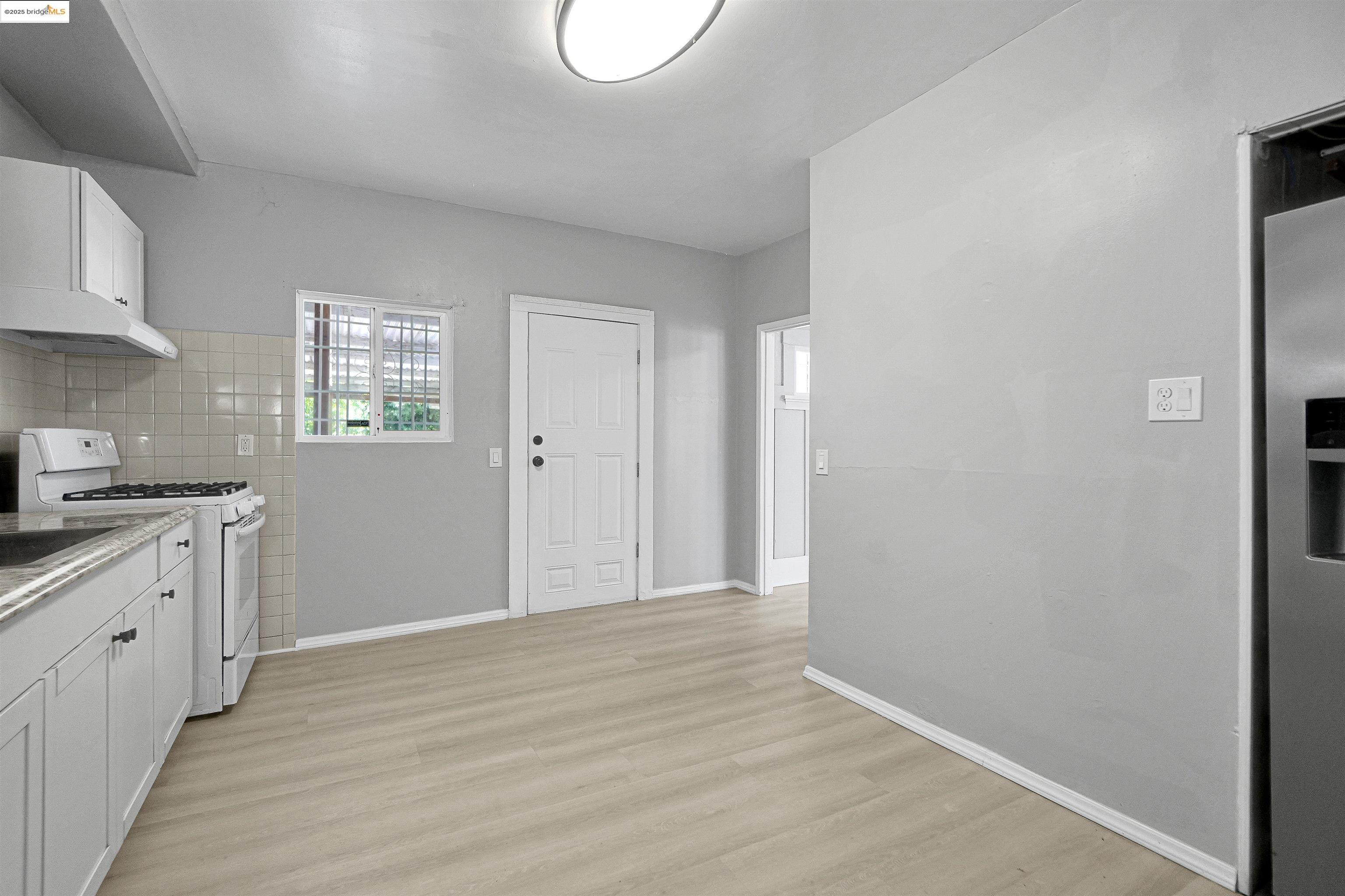 2207 East 19th Street Oakland, CA 94606 - Photo 12 of 30 a view of an empty room with window and wooden floor