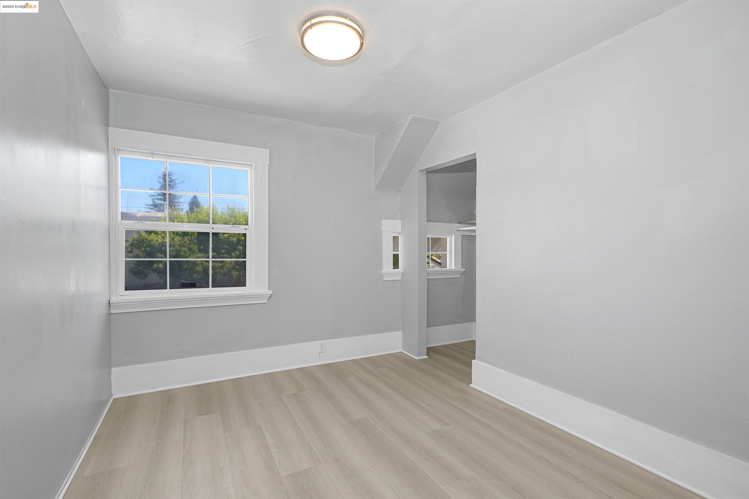 2207 East 19th Street Oakland, CA 94606 - Photo 16 of 30 an empty room with wooden floor and windows