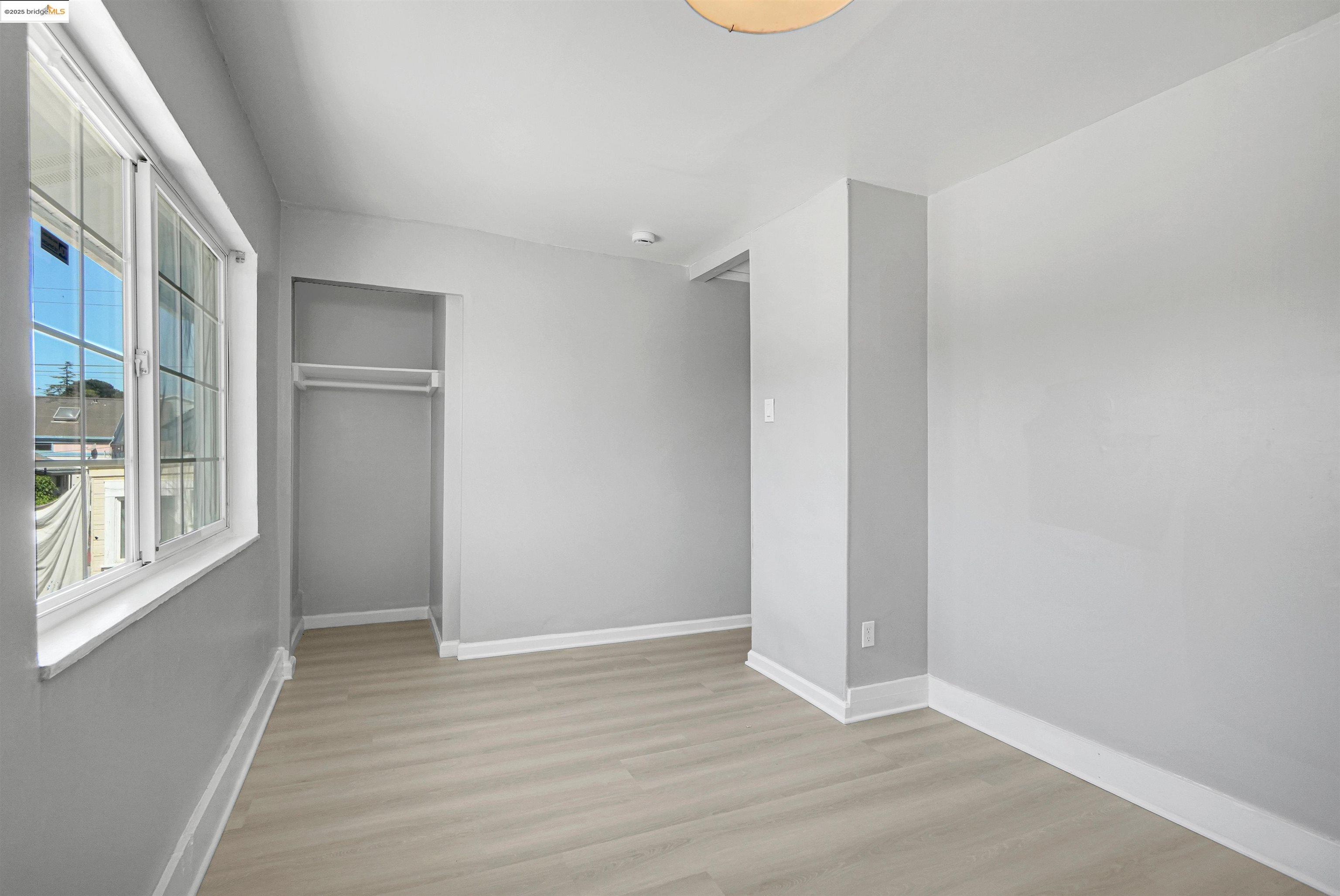 2207 East 19th Street Oakland, CA 94606 - Photo 21 of 30 a view of an empty room with wooden floor and a window