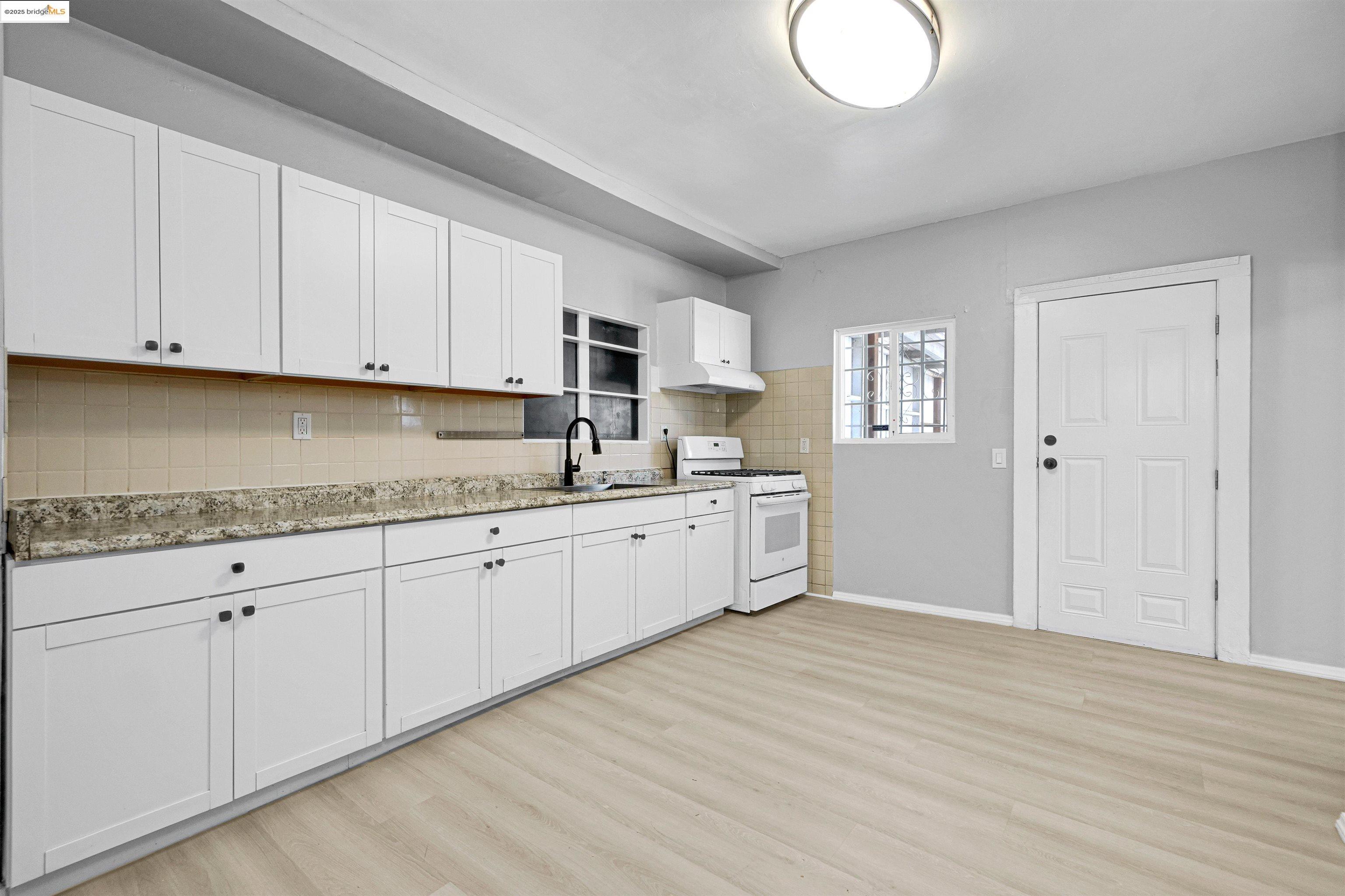 2207 East 19th Street Oakland, CA 94606 - Photo 10 of 30 a kitchen with granite countertop white cabinets and white appliances