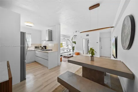 a living room with kitchen island a stove a refrigerator and a dining table with wooden floor