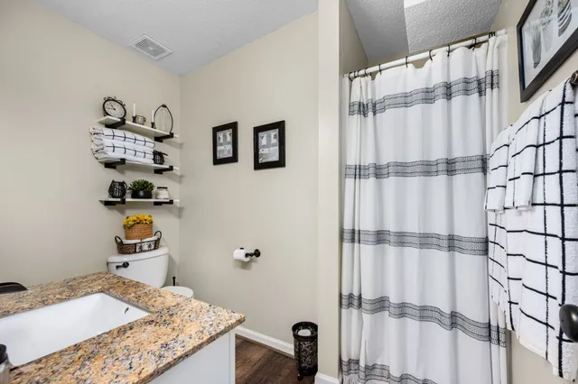 a bathroom with a granite countertop toilet sink and mirror