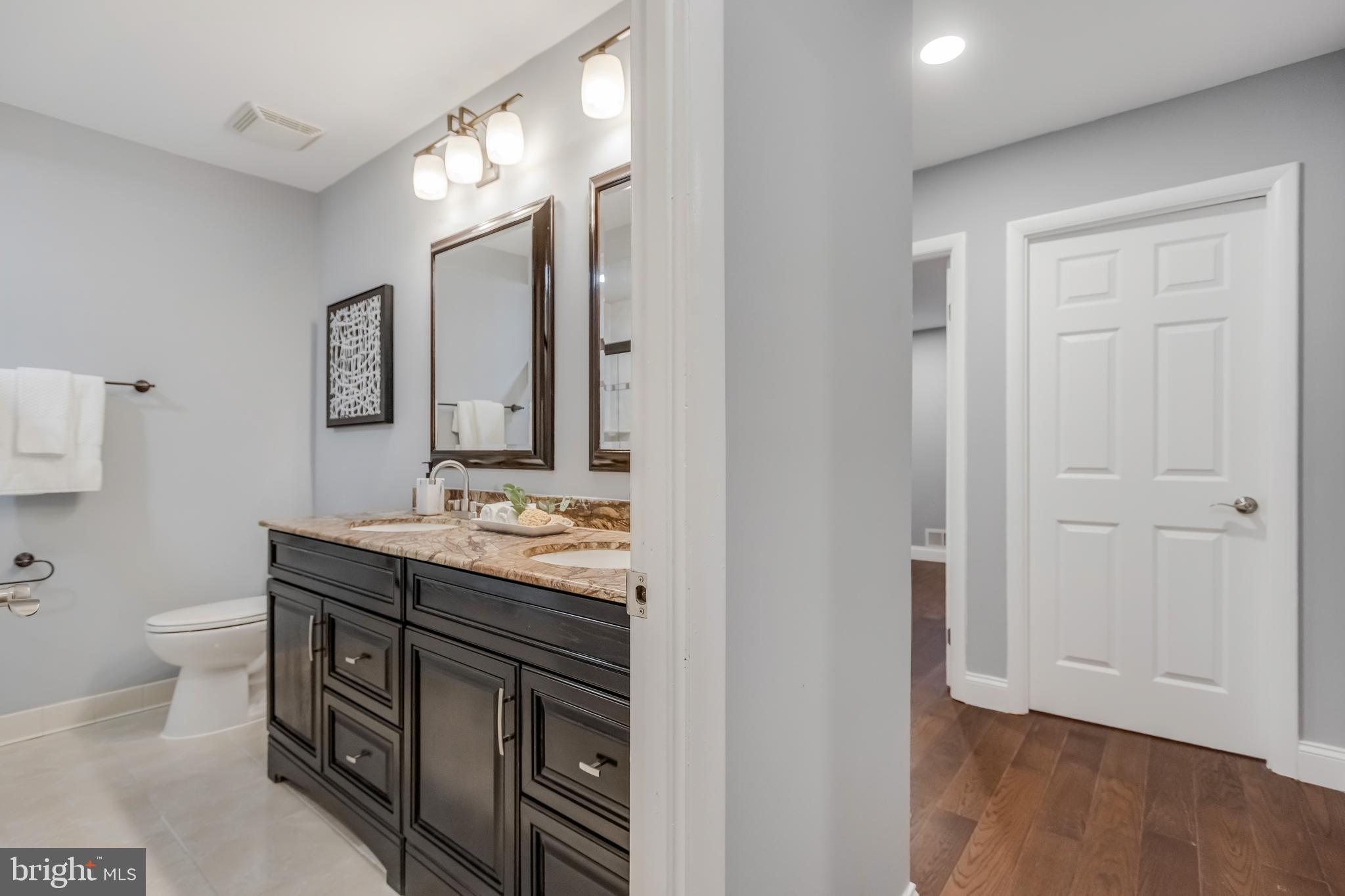 11208 Old Post Road Potomac, MD 20854 - Photo 40 of 52 a bathroom with a granite countertop toilet a sink and a mirror