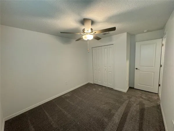 an empty room with closet and a ceiling fan