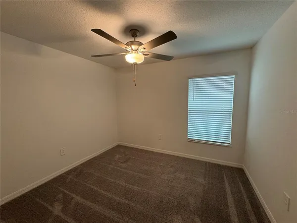 an empty room with a window and a fan
