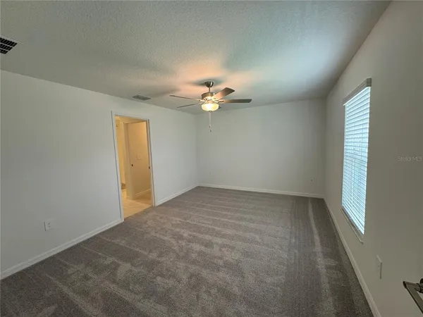 an empty room with a ceiling fan and a window
