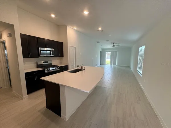 a large kitchen with stainless steel appliances a large counter top a stove a microwave a refrigerator a sink and a refrigerator