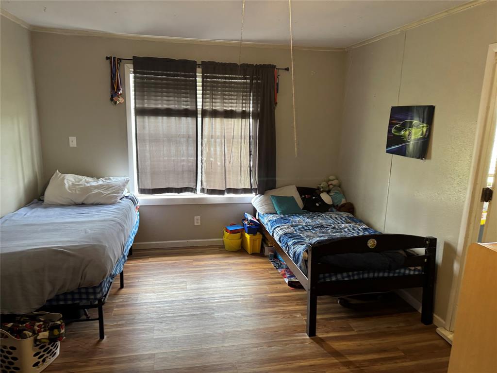 1020 Southeast 10th Street Cooper, TX 75432 - Photo 6 of 11 a bedroom with a bed and wooden floor