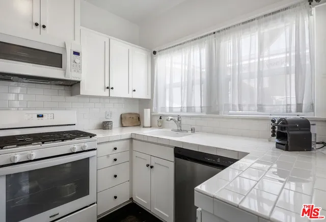 a kitchen with stainless steel appliances white cabinets and a stove top oven