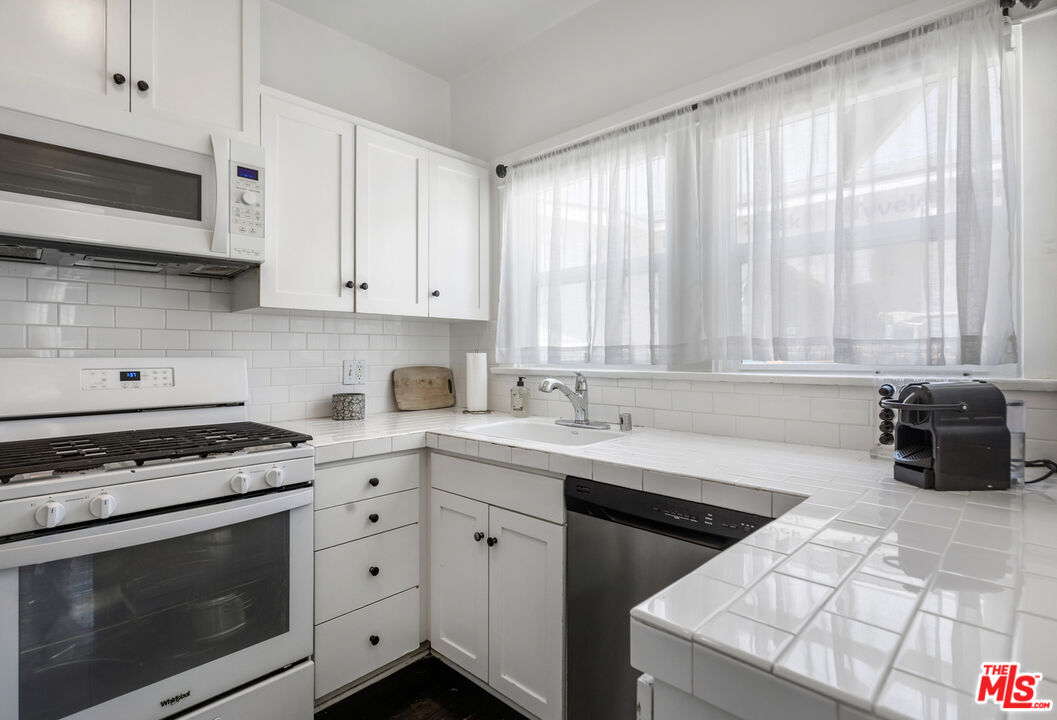 1120 West Edgeware Road Los Angeles, CA 90026 - Photo 11 of 32 a kitchen with stainless steel appliances white cabinets and a stove top oven