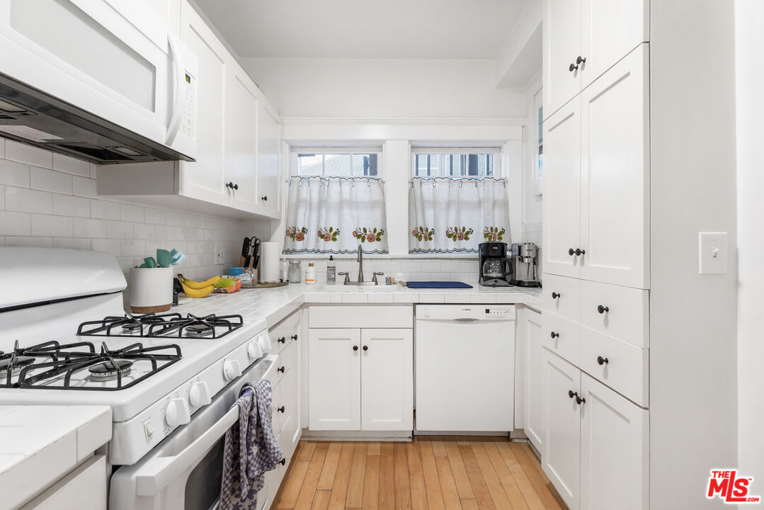 1120 West Edgeware Road Los Angeles, CA 90026 - Photo 6 of 32 a kitchen with stainless steel appliances a white stove top oven a sink a chimney and cabinets