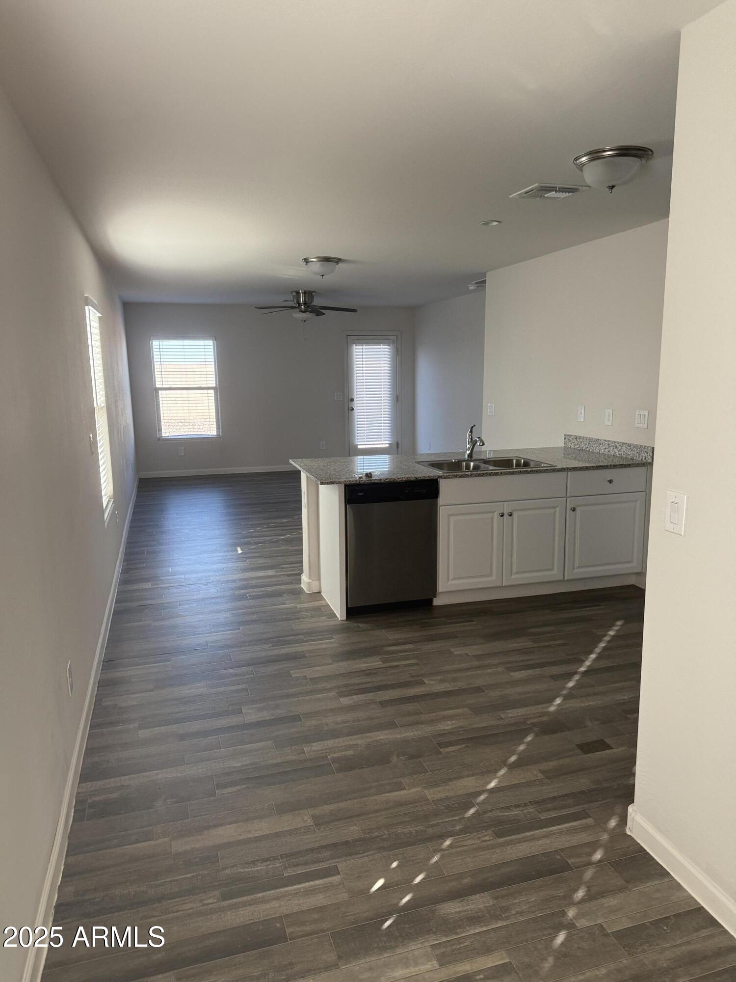 1098 South 11th Street Coolidge, AZ 85128 - Photo 6 of 20 an empty room with wooden floor and kitchen view