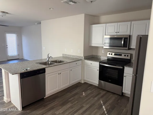 a kitchen with granite countertop stainless steel appliances a sink cabinets and a counter space