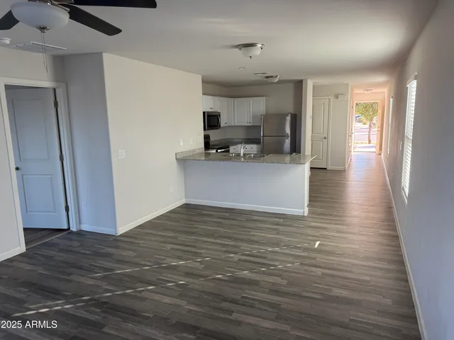 a view of kitchen and empty room with wooden floor