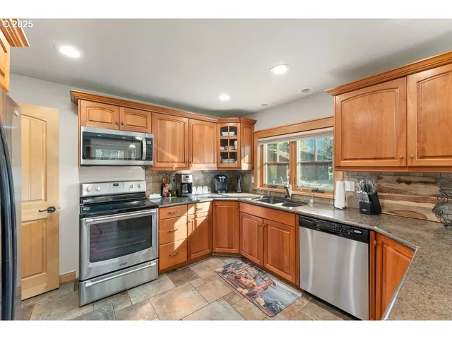 a kitchen with stainless steel appliances granite countertop a stove a sink and a microwave