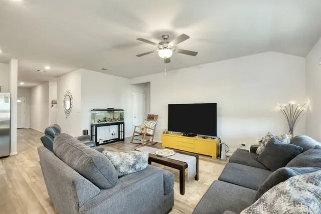 a living room with furniture and a flat screen tv with kitchen view