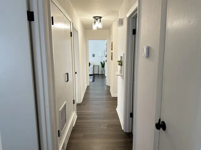 a view of a hallway with wooden floor and a bathroom