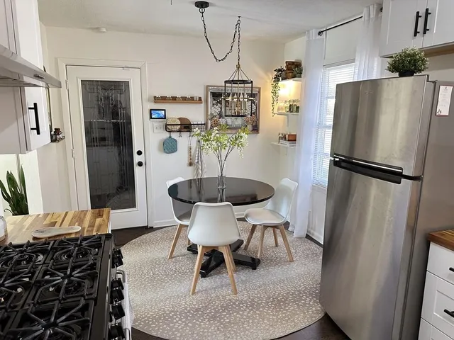 a kitchen with stainless steel appliances granite countertop a refrigerator a stove a dining table and chairs