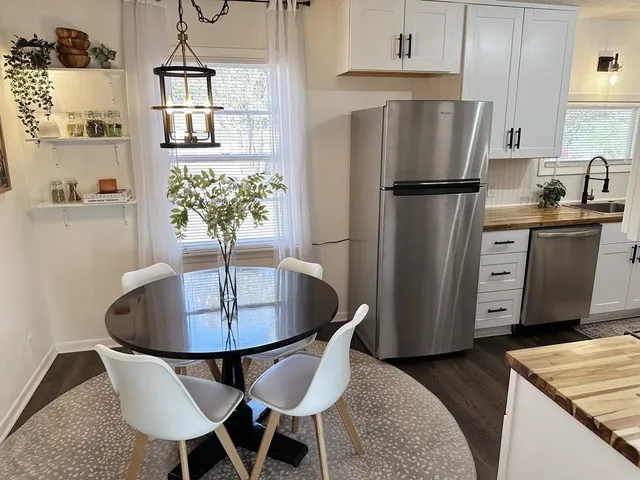 a kitchen with stainless steel appliances granite countertop a dining table chairs and a refrigerator