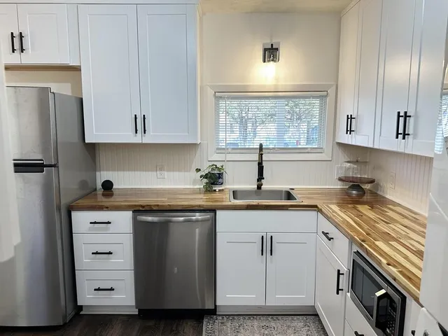 a kitchen with cabinets appliances a sink and a window