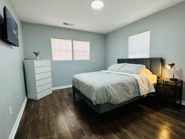 a bedroom with a bed and a flat tv screen on dresser