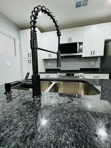 a kitchen with a sink a microwave and cabinets