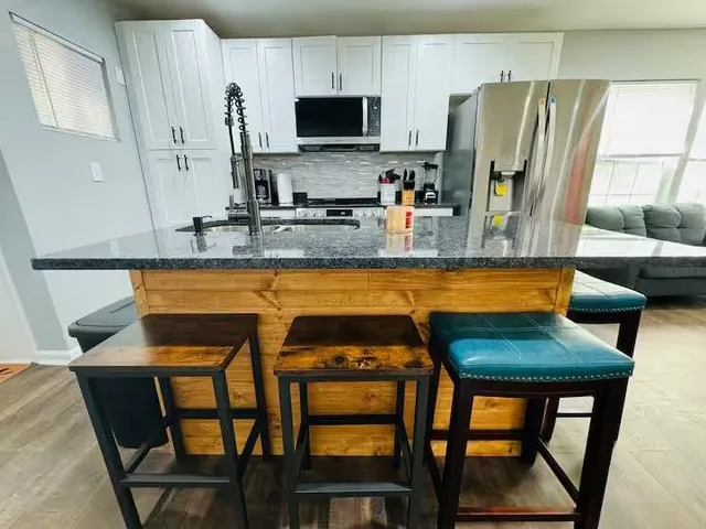 a kitchen with stainless steel appliances granite countertop table chairs sink and cabinets