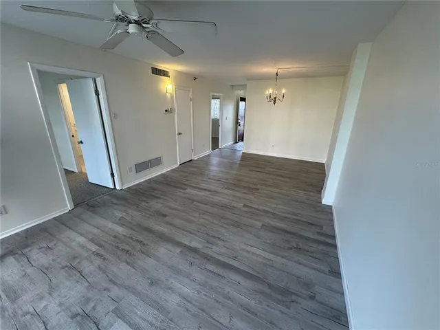 an empty room with wooden floor and a ceiling fan