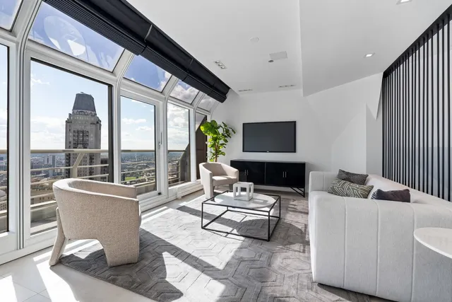 a living room with couches chairs and kitchen view with wooden floor