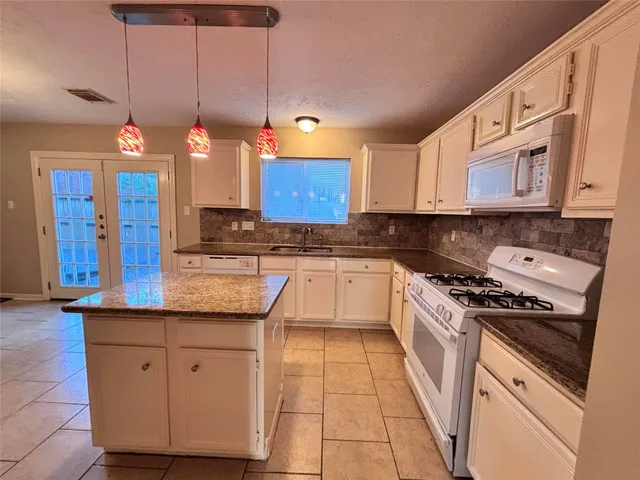 a kitchen with granite countertop wooden cabinets and white appliances
