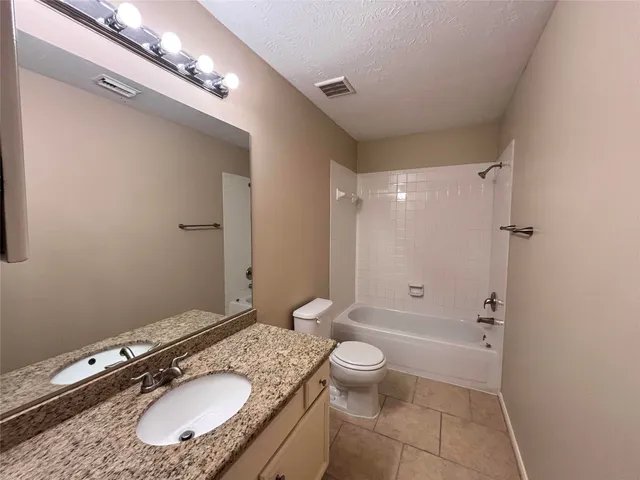 a bathroom with a granite countertop sink a toilet a mirror and shower